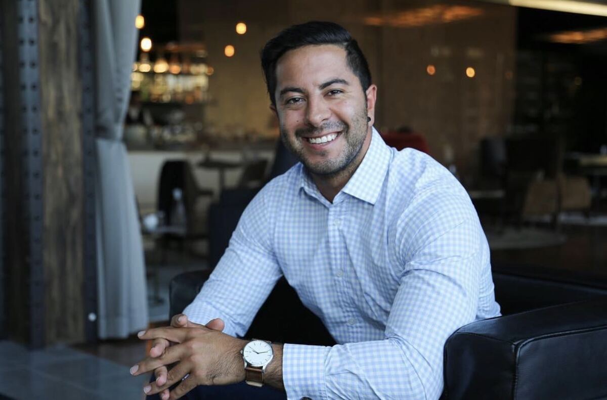 Adam Agresta in a business shirt, smiling, seated in a Sydney bar
