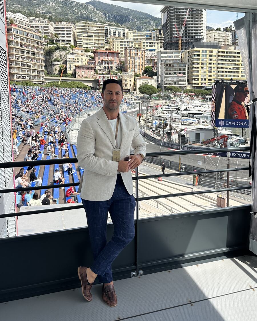 Adam Agresta in a cream blazer on a terrace overlooking the harbour in Monaco